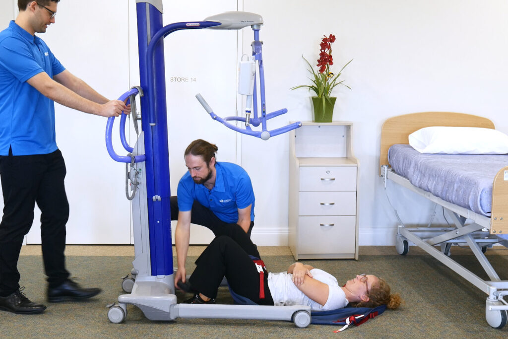 Two clinicians transferring a client off the floor with a hoist