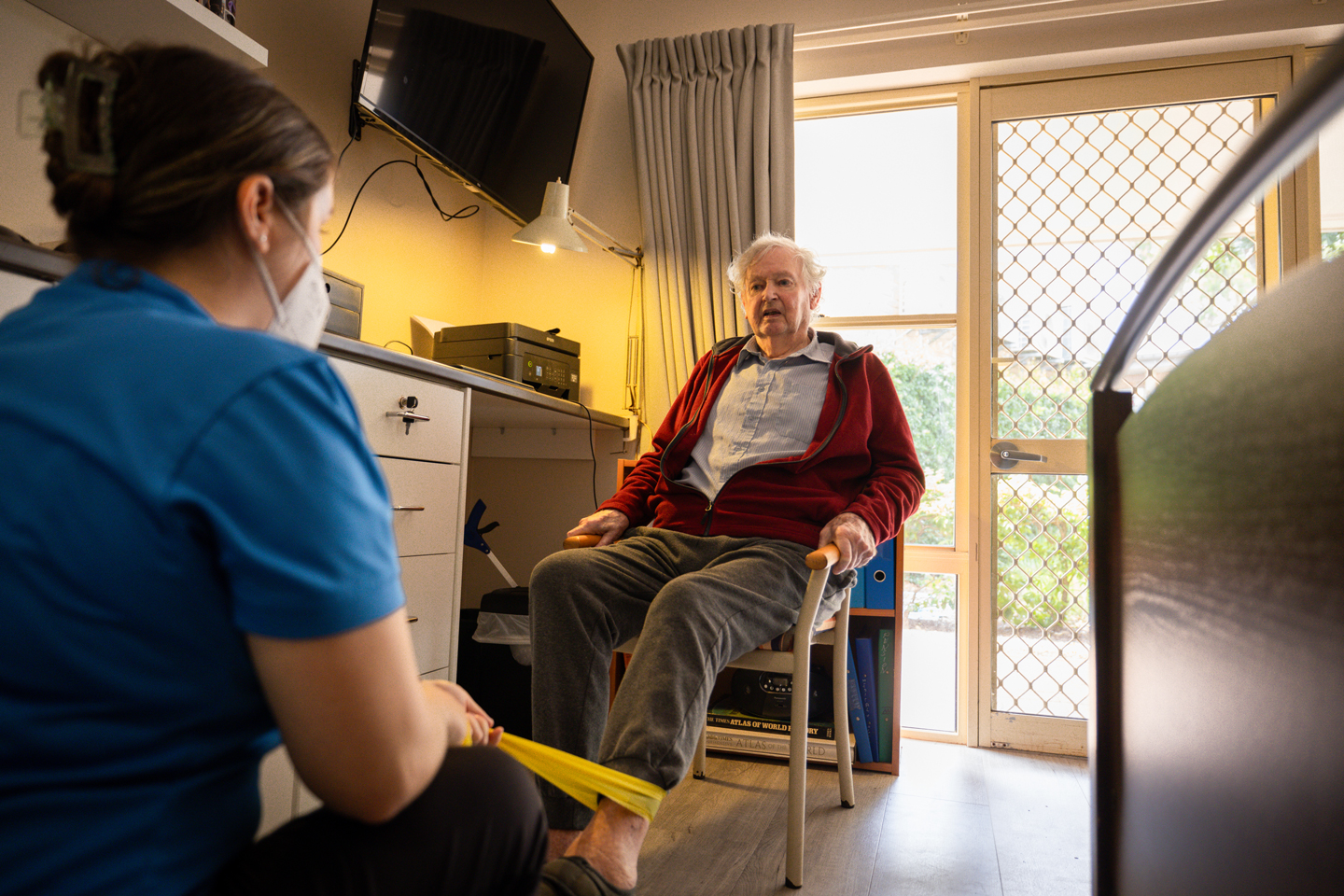 Physiotherapist and older adult doing lower limb resistance exercises