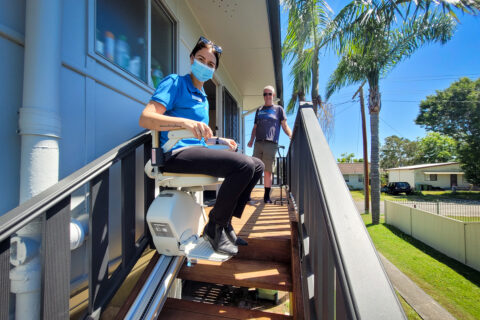 Occupational Therapist showing an NDIS client how to use his newly installed stair lift.